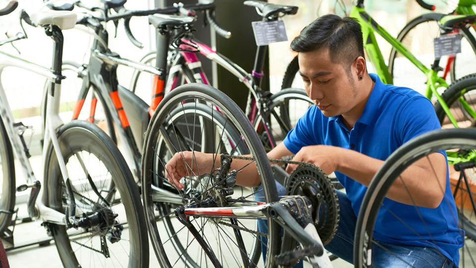 erkäufer in Uniform passt Fahrradkette an die er im Laden verkauft