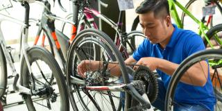 erkäufer in Uniform passt Fahrradkette an die er im Laden verkauft
